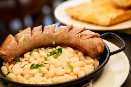 A serving of tapas consisting of white beans and grilled sausageの写真素材