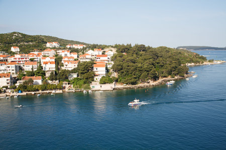 Pilot boat cruising past coastal homes on the coast of Croatia in Dubrovnikの写真素材