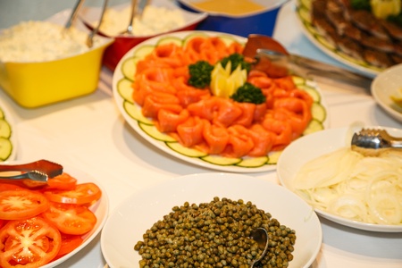 Smoked salmon on buffet with sliced tomatoes, onions and capersの写真素材