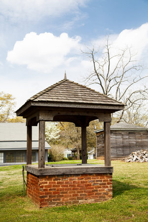 An old brick well in the backyard behind a barn and woodpileの写真素材