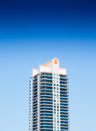 A solo modern condo tower with balconies under a clear blue sky