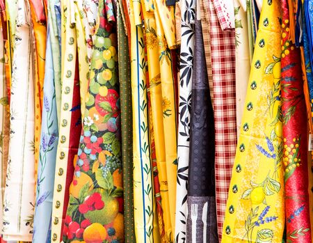An assortment of colorful tablecloths hanging on a rack in a marketの写真素材