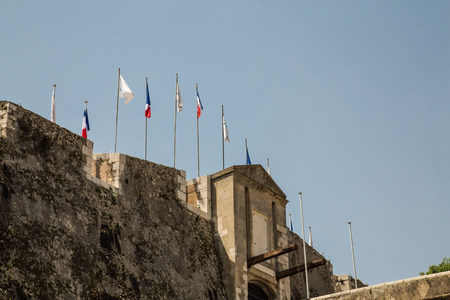 Flags in calm wind over a stone fortress under clear blue skiesの写真素材