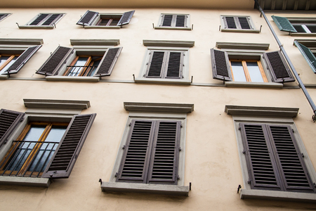 An old plaster building in Florence with windows and brown shuttesの写真素材