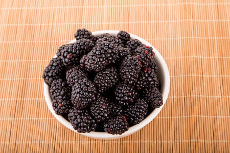 A white bowl full of fresh, ripe blackberriesの写真素材