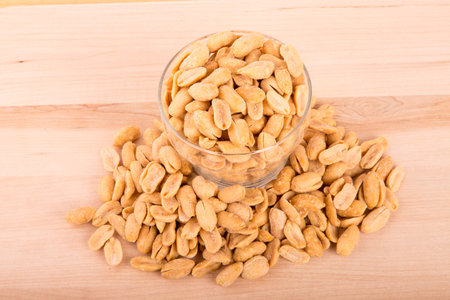 A glass bowl of peanuts on a wood table