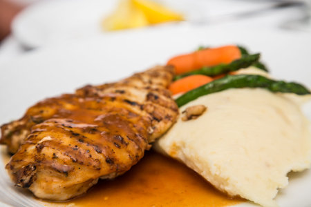 Grilled chicken breast with gravy, mashed potatoes, asparagus and carrotsの写真素材