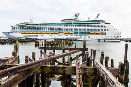 A modern, luxury cruise ship docked in a harbor beyond old wood pilings from a dockの写真素材