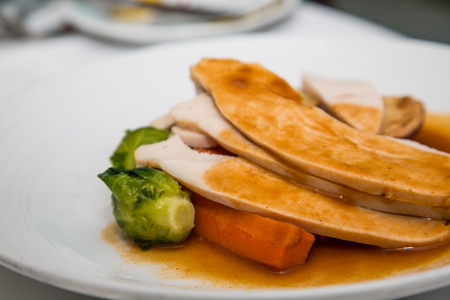 Sliced turkey with gravy on a white plate with brussel sprouts and carrotsの写真素材