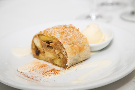 Apple tart on white plate garnished with cinammon with a scoop of ice creamの写真素材