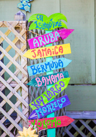 A colorful sign at the beach pointing to other tropical beaches