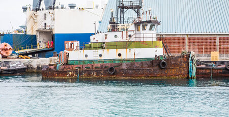An old rusty tugboat tied up to a pier in Nassau, Bahamasの写真素材