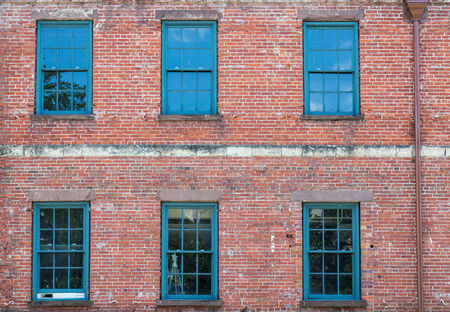 Old green wood windows in a brick buildingの写真素材