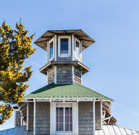 An old cupola on a home under blue skies of wood and green shinglesの写真素材