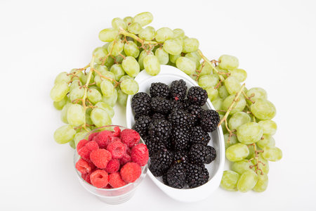 Fresh, whole fruit on a white background. Raspberries Blackberries and Grapes on White