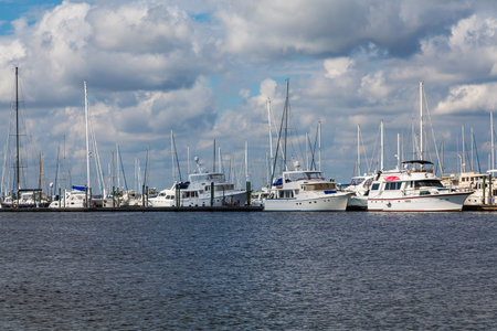 White yachts and sailboats in a marina under cloudy skies
