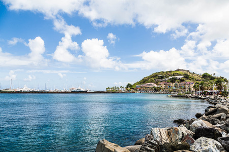 A rock seawall curving toward a modern shopping mall and a luxury yacht marinaの写真素材