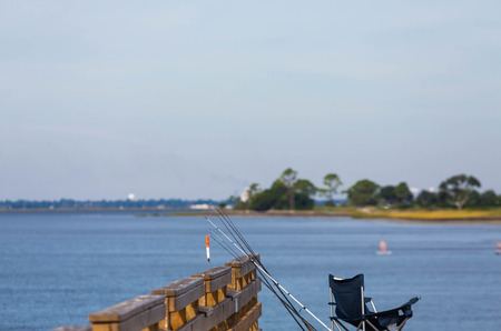 Fishing poles leaning against a pier over a calm seaの写真素材