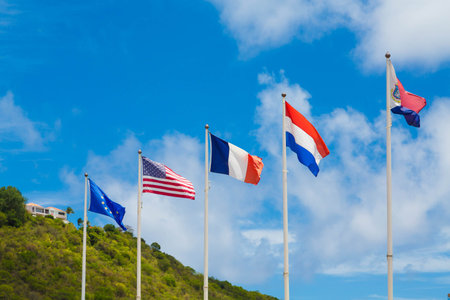 Five international flags flying under blue sky in the Caribbean