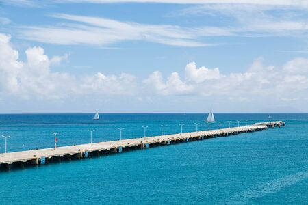 Concrete pier extending far into clear aqua water of the Caribbeanの写真素材