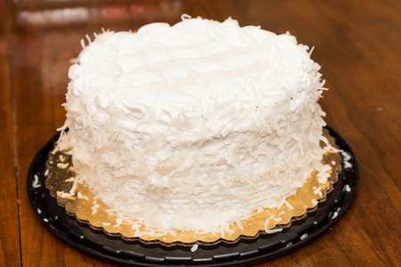 A fresh baked coconut cake in a plate on a wood tableの写真素材