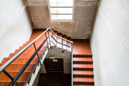 Staircase in cement stairwell with quarry tile steps and black iron railingsの写真素材