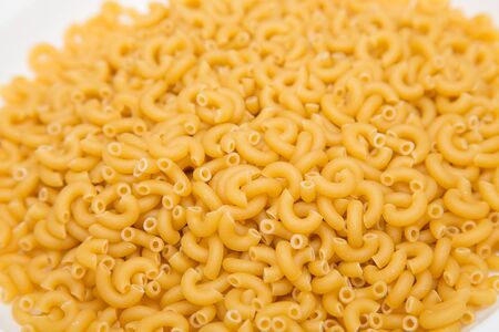 Dried elbow macaroni on a counter for background or textureの写真素材