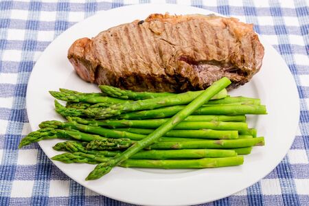 Grilled strip steak on a white plate with asparagusの写真素材