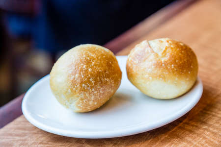 Two baked rolls on a plate and tableの写真素材