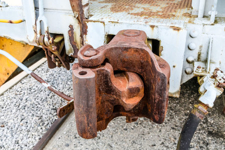 An old rusty railroad car coupler over gravel