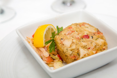 An appetizer of crab cake with lemon wedge and parsleyの写真素材