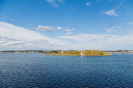 White lighthouse on bay near Halifax, Nova Scotia across blue bayの写真素材