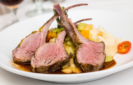 Three medium rare lamb chops on a bed of vegetablesの写真素材