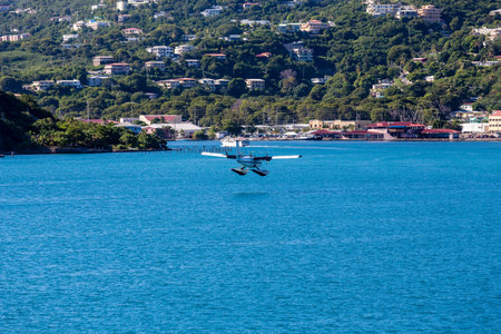 Small seaplane about to land on blue water in bay