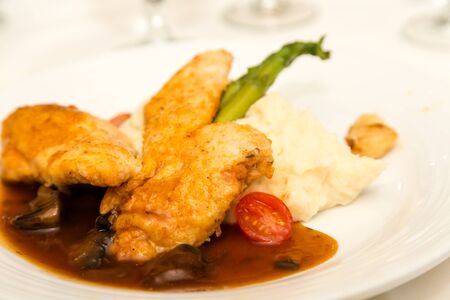 A dinner of chicken marsala with mashed potatoes and asparagusの写真素材
