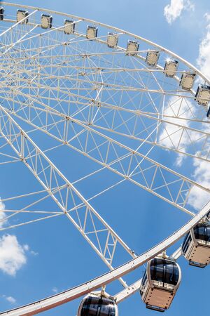 A modern white Ferris wheel against brilliant blue skyの写真素材