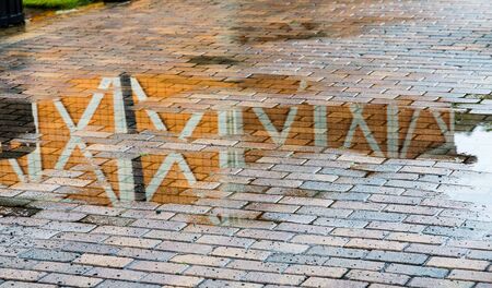 A wood wall reflected in a rain puddle in a brick sidewalkの写真素材