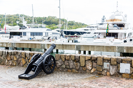 An old black, iron cannon at a wall in a marinaの写真素材