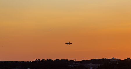 Airplanes descending toward airport at sunsetの写真素材