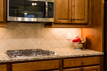 A new gas cooktop on a granite countertop with a tile backsplashの写真素材