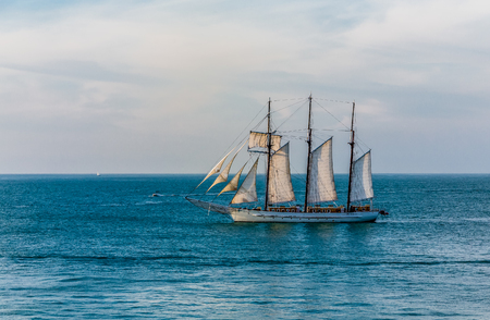 Schooner under sails sailing across a bay under beautiful skiesの写真素材