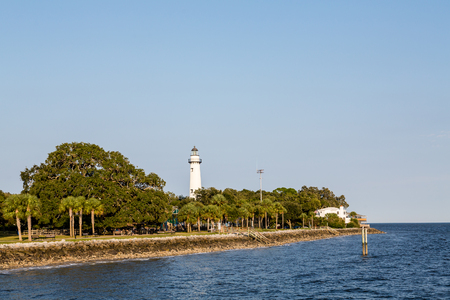 Trees along a green park on the coast with white lighthouseの写真素材