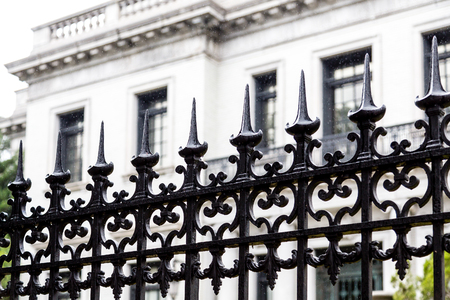 Black Wrought Iron Fence by White Buildingの写真素材