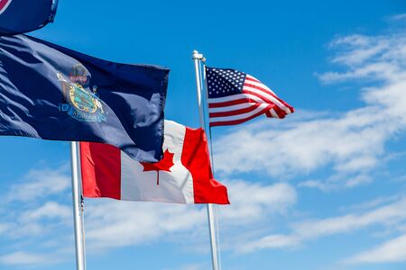 Flags of Maine, Canada and United States waving under a blue skyの写真素材