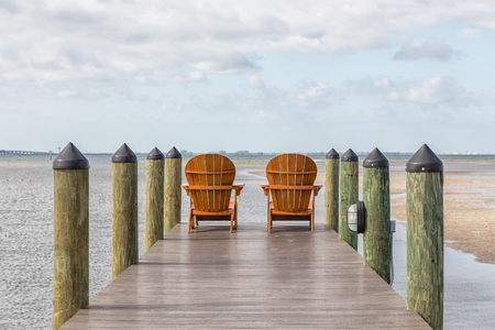 Adirondack chairs on a wooden pier in the tropicsの写真素材