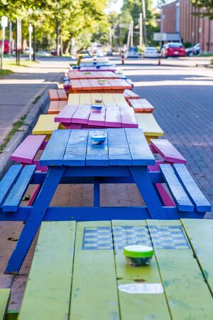 A line of colorful wooden picnic tables in the street in Charlottetown, Canadaの写真素材