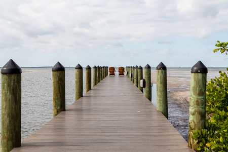 Adirondack chairs on a wooden pier in the tropicsの写真素材