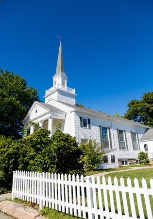 White Church Beyond Picket Fence under blue skyの写真素材