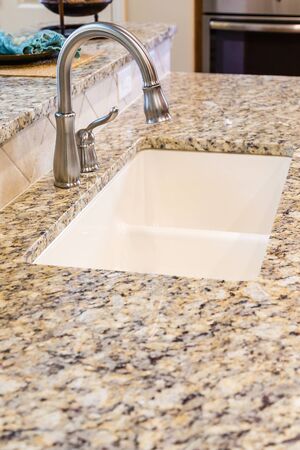 Modern Stainless Steel Faucet on Granite Kitchen Counter in New Homeの写真素材