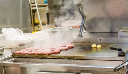 Burgers Smoking on Griddle in commercial Kitchenの写真素材